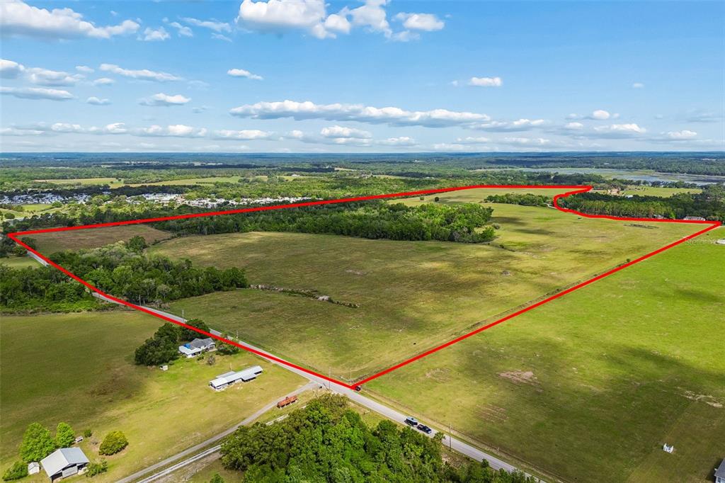 An aerial view shows a large, open grassy field outlined in red — BAYHEAD ROAD Lot 7, DADE CITY, FL
