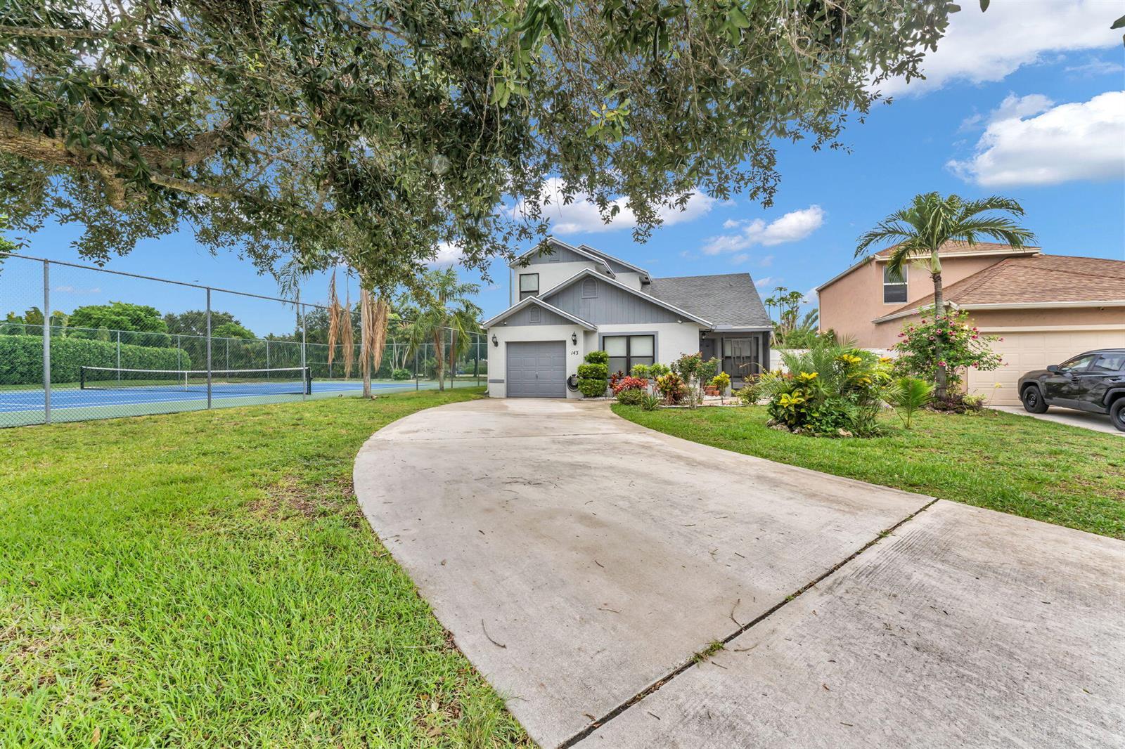 A two-story house with a concrete driveway and an adjacent tennis court — 143 W Tara Lakes Dr Drive W, Boynton Beach FL 33436, BOYNTON BEACH, FL
