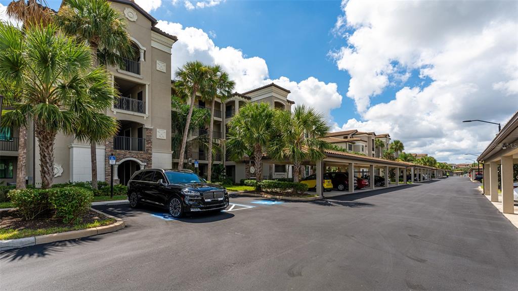 A black SUV is parked in front of a multi-story apartment building with covered parking — 17108 VARDON TERRACE UNIT 206, BRADENTON, FL