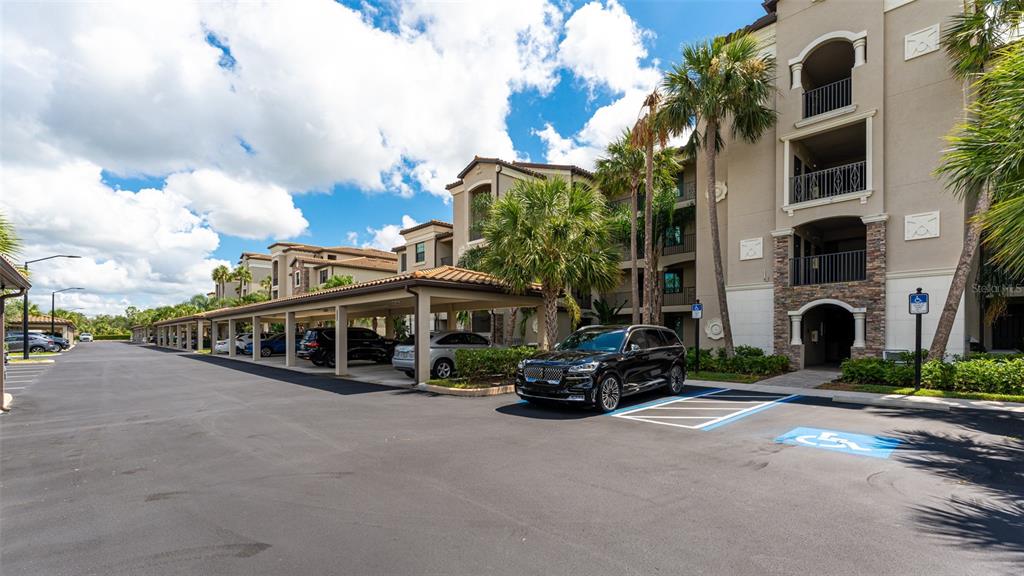A multi-story apartment building with covered parking spaces and a handicap-accessible spot in front — 17108 VARDON TERRACE UNIT 206, BRADENTON, FL