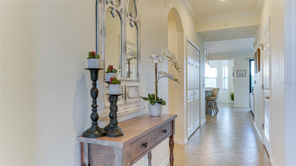 A hallway features a wooden console table with decor, a decorative mirror, and tile flooring — 17108 VARDON TERRACE UNIT 206, BRADENTON, FL