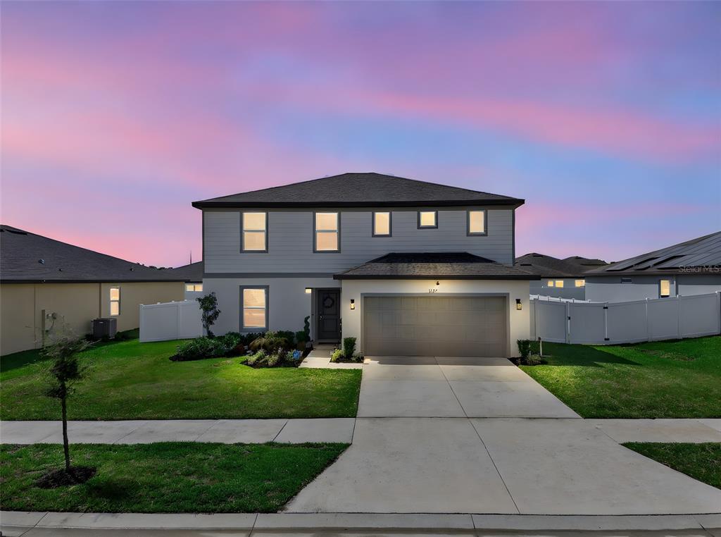 The backyard of a two-story house features a covered patio and a white vinyl fence — 1117 MICHELANGELO LANE, WINTER HAVEN, FL