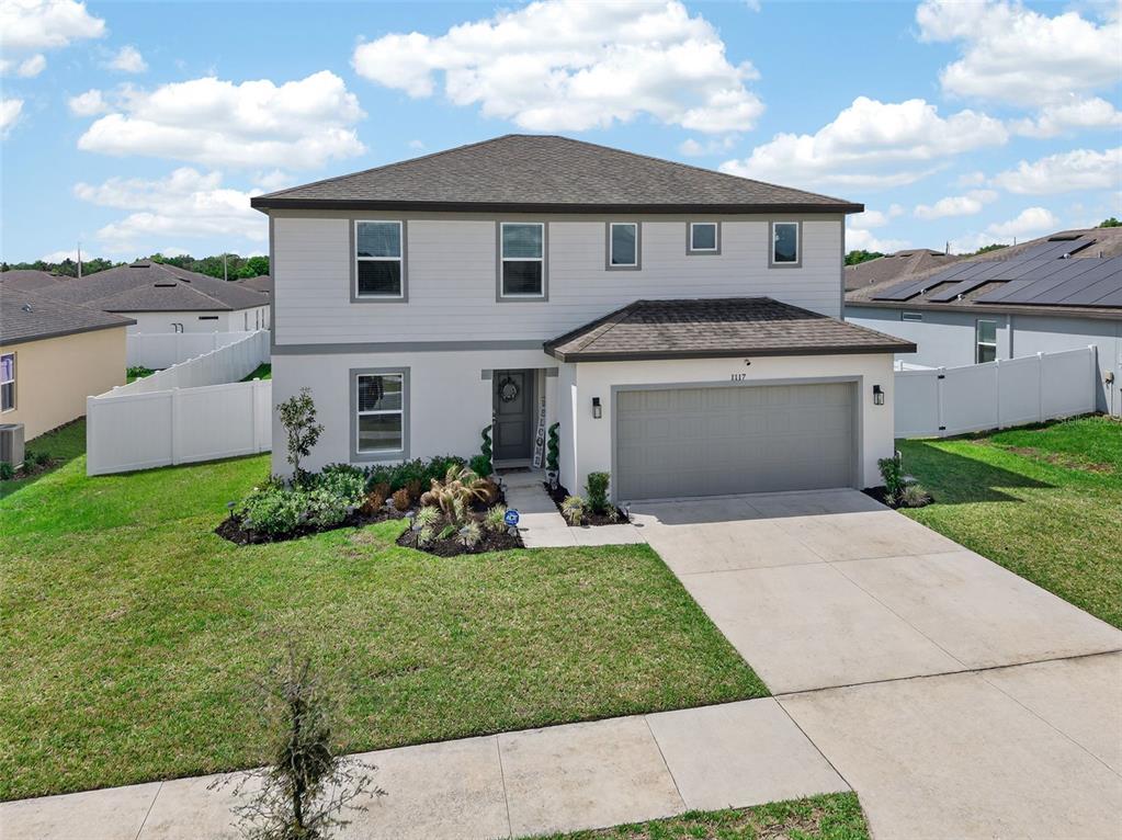 A two-story house with a gray garage, white siding, and a landscaped front yard — 1117 MICHELANGELO LANE, WINTER HAVEN, FL
