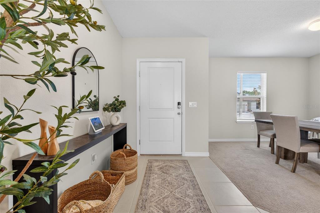 An entryway features a console table, woven baskets, a runner rug, and a white door — 1117 MICHELANGELO LANE, WINTER HAVEN, FL