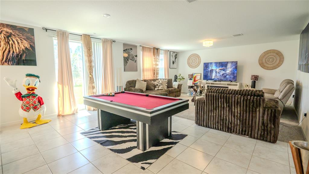 A living room features a pool table, a brown sofa, a television, and tile flooring — 3198 VICEROY COURT, POINCIANA, FL