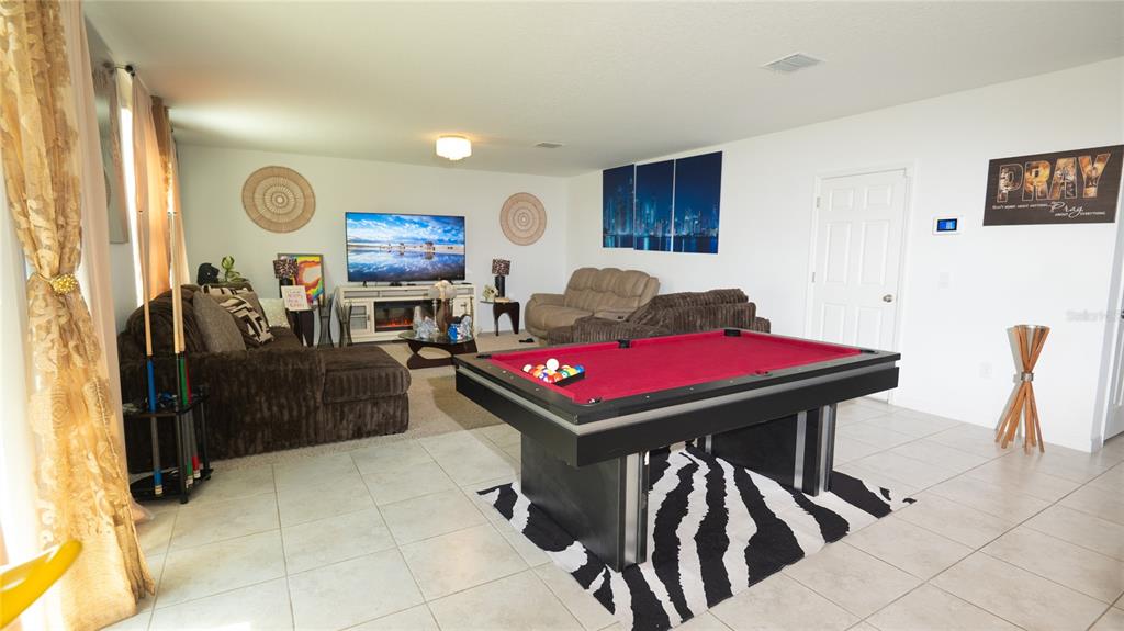 A living room features a pool table, a brown sectional sofa, and a television console — 3198 VICEROY COURT, POINCIANA, FL
