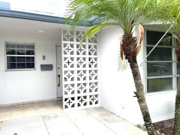 A white exterior wall features a decorative breeze block screen next to a front door — 1152 Circle Drive # D, Delray Beach FL 33445, DELRAY BEACH, FL