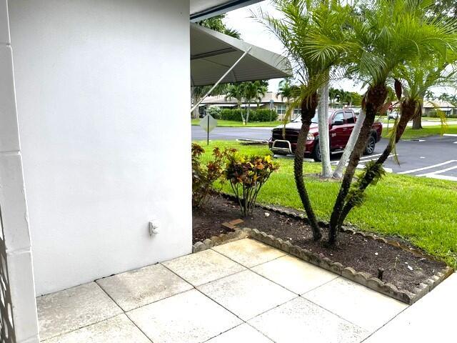 A paved patio sits beside a white wall with a small palm tree in the foreground — 1152 Circle Drive # D, Delray Beach FL 33445, DELRAY BEACH, FL