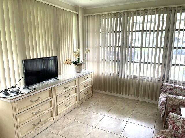 A room features a television on a long dresser, vertical blinds, and tile flooring — 1152 Circle Drive # D, Delray Beach FL 33445, DELRAY BEACH, FL