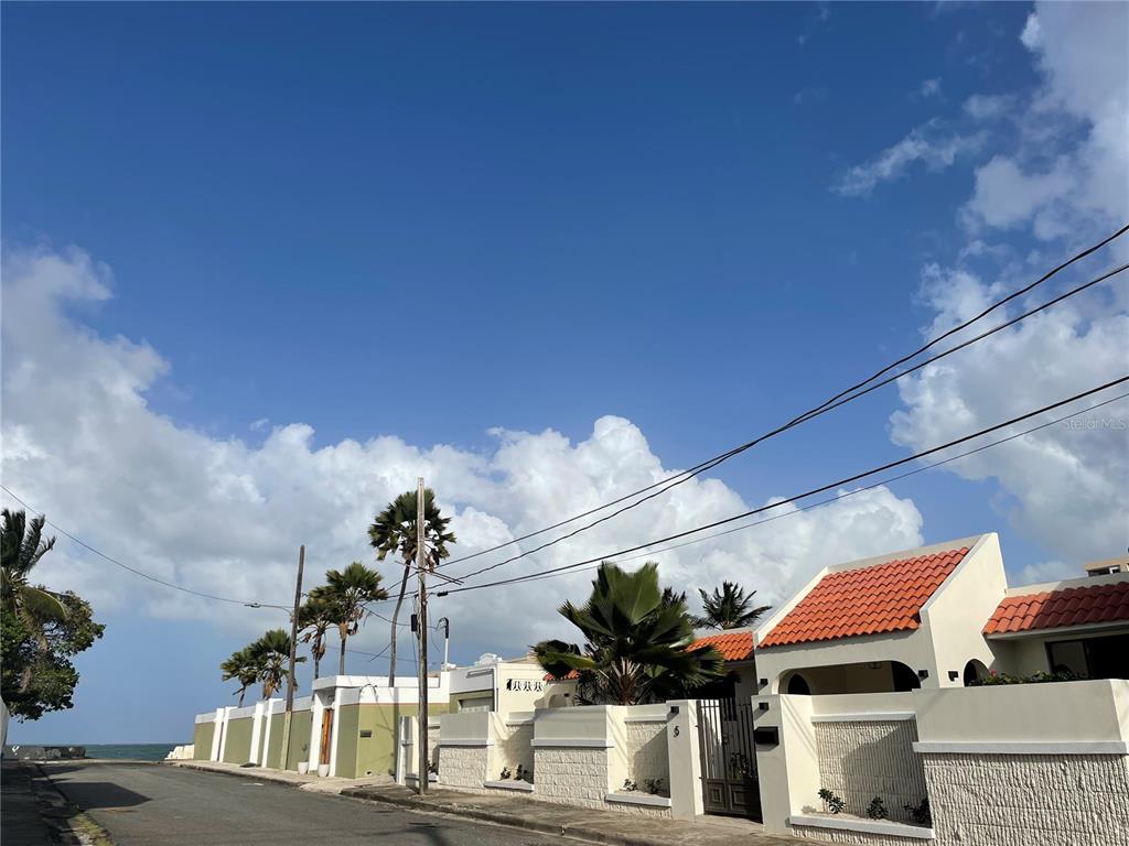 An aerial view shows several coastal houses with flat roofs, swimming pools, and palm trees — 5 HISTELA, PUNTA LAS MARIAS, SAN JUAN, PR