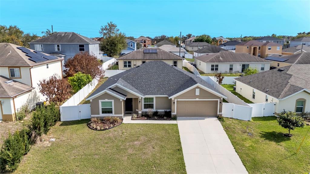 An aerial view of a single-story suburban house with a tan exterior and gray roof — 310 ATHABASCA PLACE, POINCIANA, FL