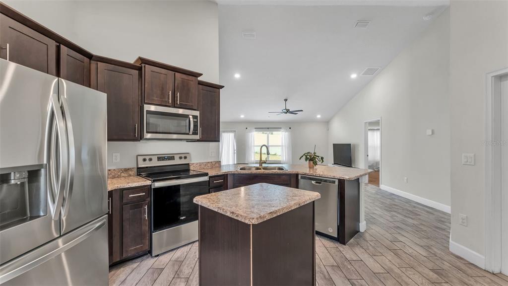 A kitchen with dark wood cabinets, stainless steel appliances, and a central island — 310 ATHABASCA PLACE, POINCIANA, FL