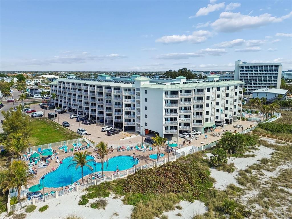 An aerial view of a multi-story beachfront condominium building with a pool and parking lot — 12000 GULF BOULEVARD UNIT 603N, TREASURE ISLAND, FL
