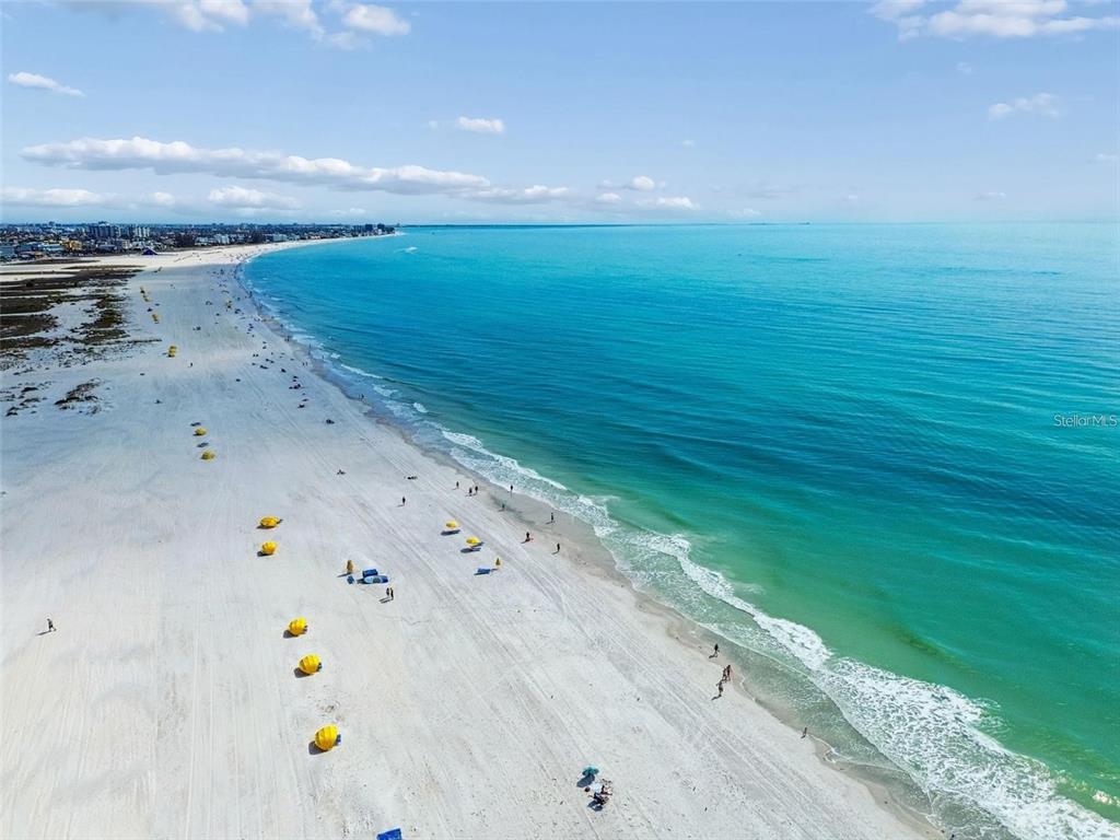 An aerial view shows a wide, white sand beach meeting the turquoise ocean water — 12000 GULF BOULEVARD UNIT 603N, TREASURE ISLAND, FL