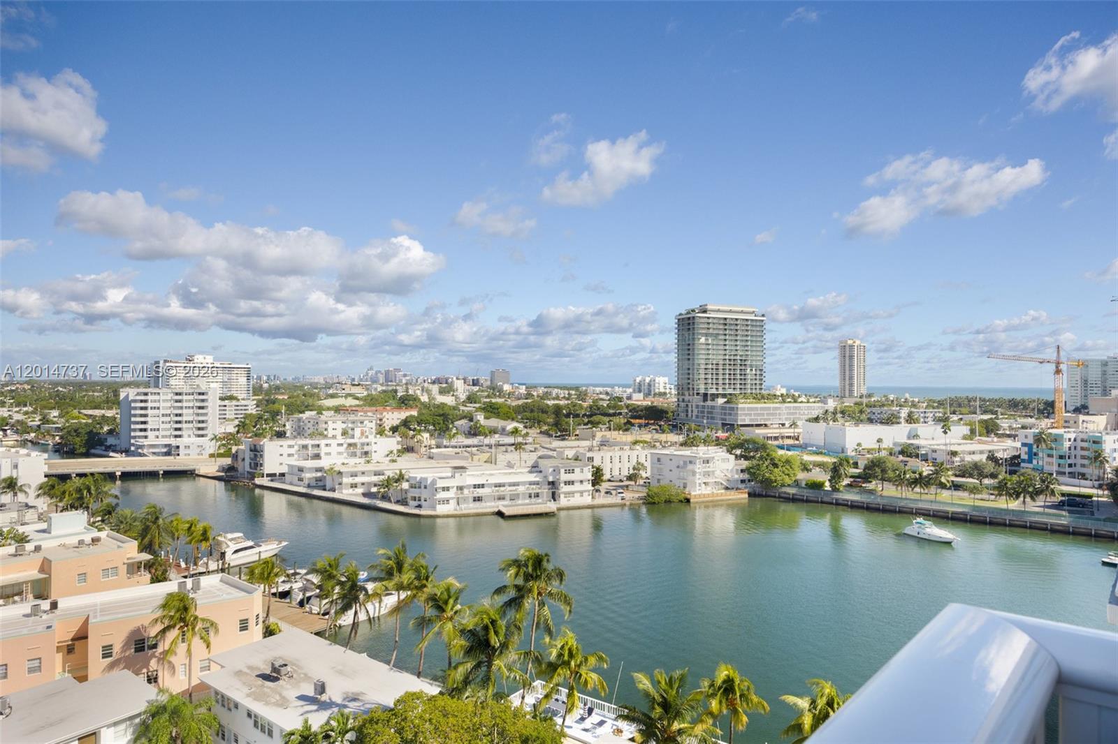 An elevated view of a waterway, palm trees, and city buildings under a blue sky — 900 Bay Dr, Miami Beach FL 33141, MIAMI BEACH, FL