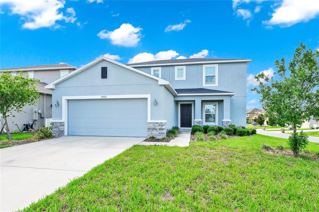 A two-story suburban house features a light blue exterior, stone accents, and a two-car garage — 3800 FESCUE STREET, CLERMONT, FL