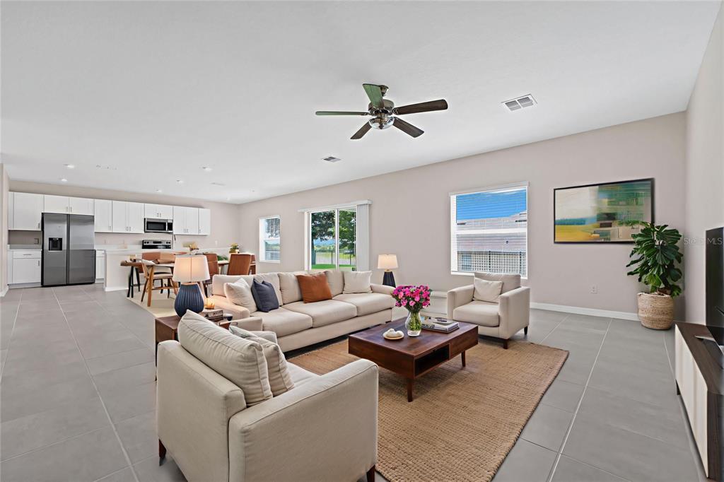 An open-concept living room features a beige sofa, two armchairs, a coffee table, and kitchen — 3800 FESCUE STREET, CLERMONT, FL
