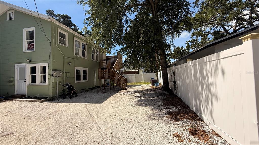 A gravel driveway leads to the side of a green two-story building with exterior stairs — 905 JONES STREET, CLEARWATER, FL