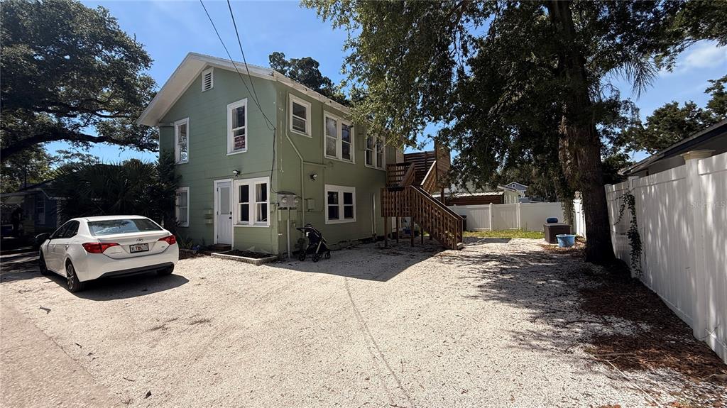 A two-story green house with a gravel driveway and an exterior wooden staircase — 905 JONES STREET, CLEARWATER, FL