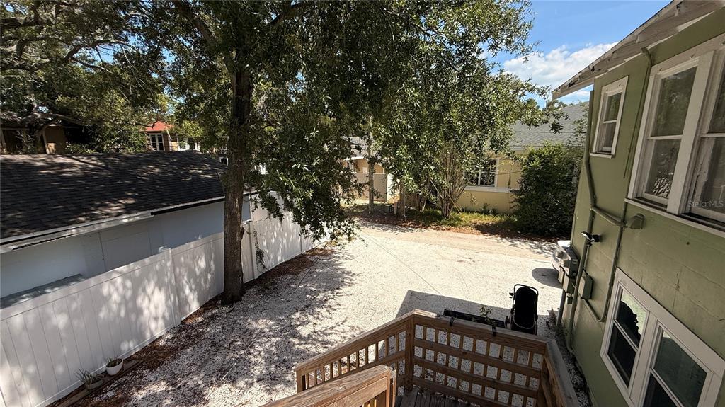 An elevated view of a gravel backyard area with a wooden deck and white fencing — 905 JONES STREET, CLEARWATER, FL