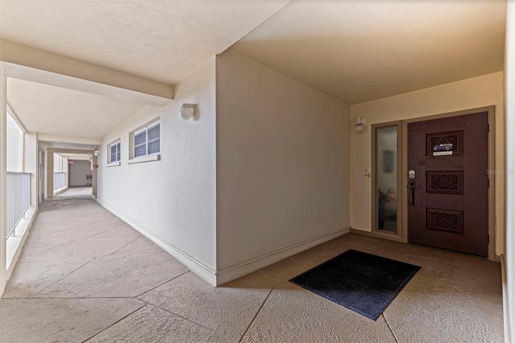 An exterior hallway leads to a dark brown front door with a side window panel — 5000 GULF BOULEVARD UNIT 301, ST PETE BEACH, FL