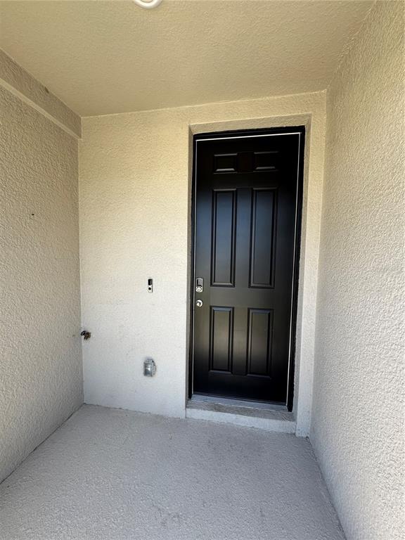 A black six-panel front door is set within a covered, stucco-walled entryway — 5860 OCEAN ISLE DRIVE, NOKOMIS, FL