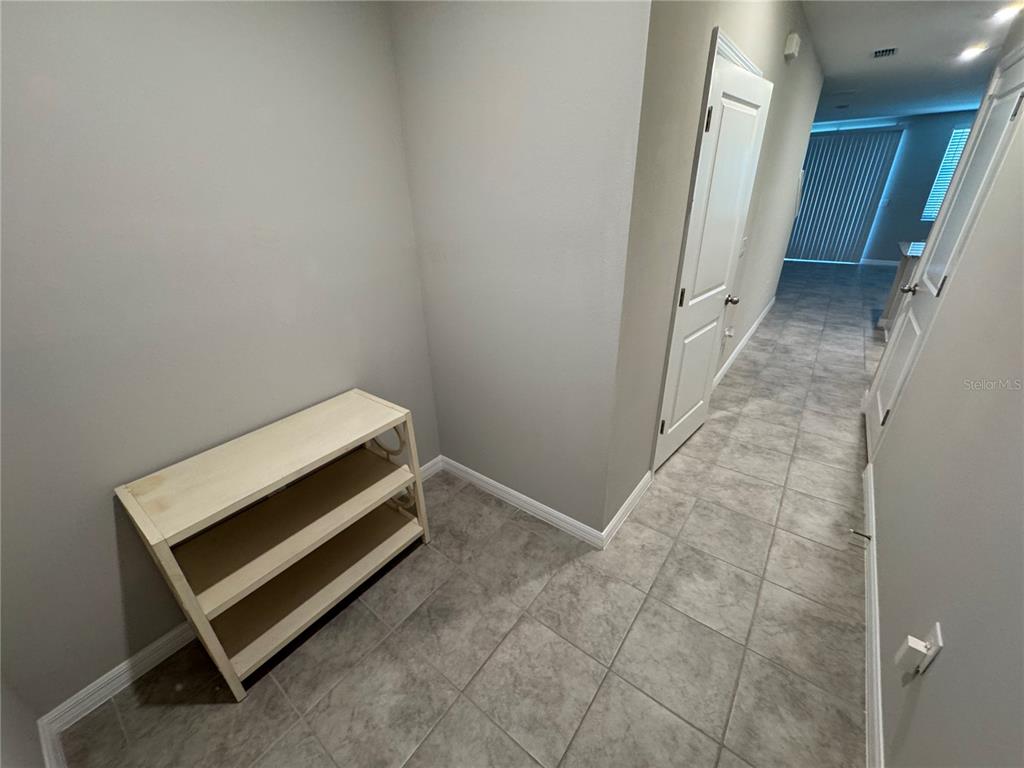 A tiled entryway features a light-colored wooden shoe rack against a gray wall — 5860 OCEAN ISLE DRIVE, NOKOMIS, FL