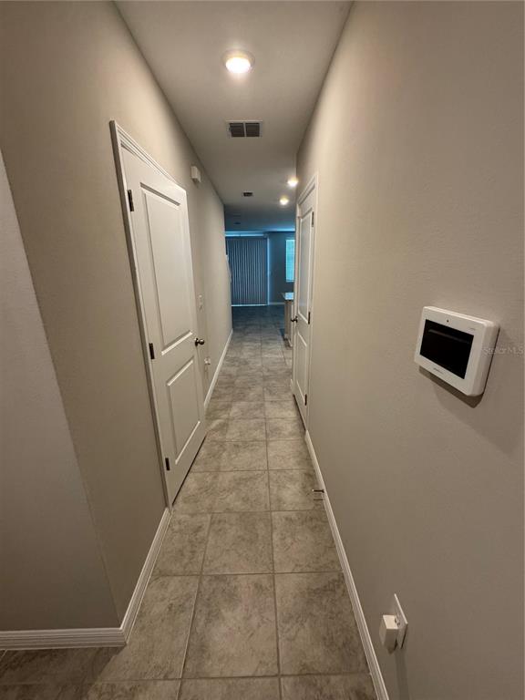 A hallway with tile flooring leads toward a bright room with sliding glass doors — 5860 OCEAN ISLE DRIVE, NOKOMIS, FL
