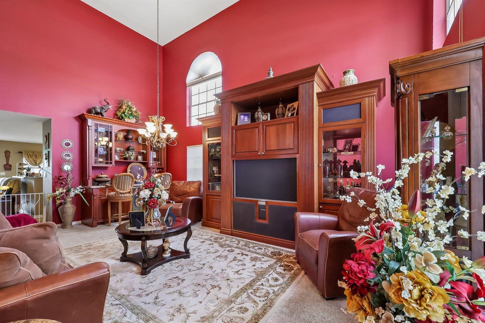 A living room features red walls, a large wooden entertainment center, and leather armchairs — 6205 Lansdowne Circle, Boynton Beach FL 33472, BOYNTON BEACH, FL