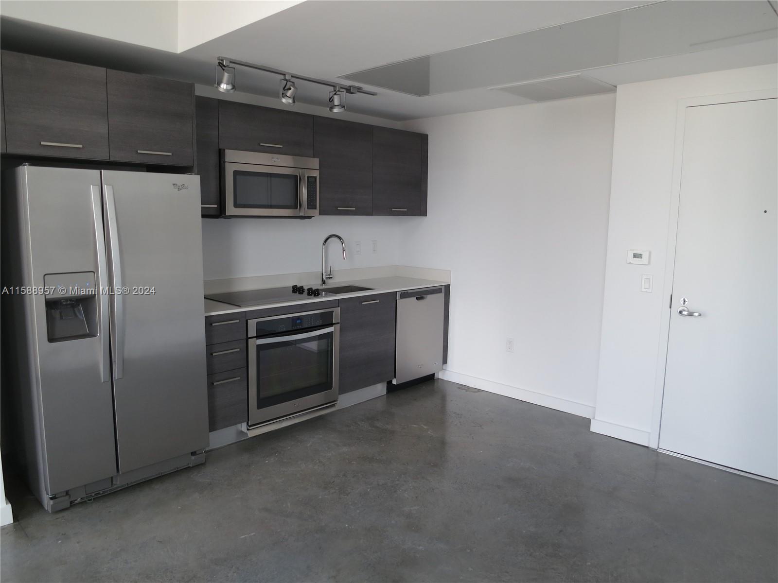 A modern kitchen features dark wood cabinets, stainless steel appliances, and polished concrete floors — 151 SE 1 St # 1704, Miami FL 33131, MIAMI, FL