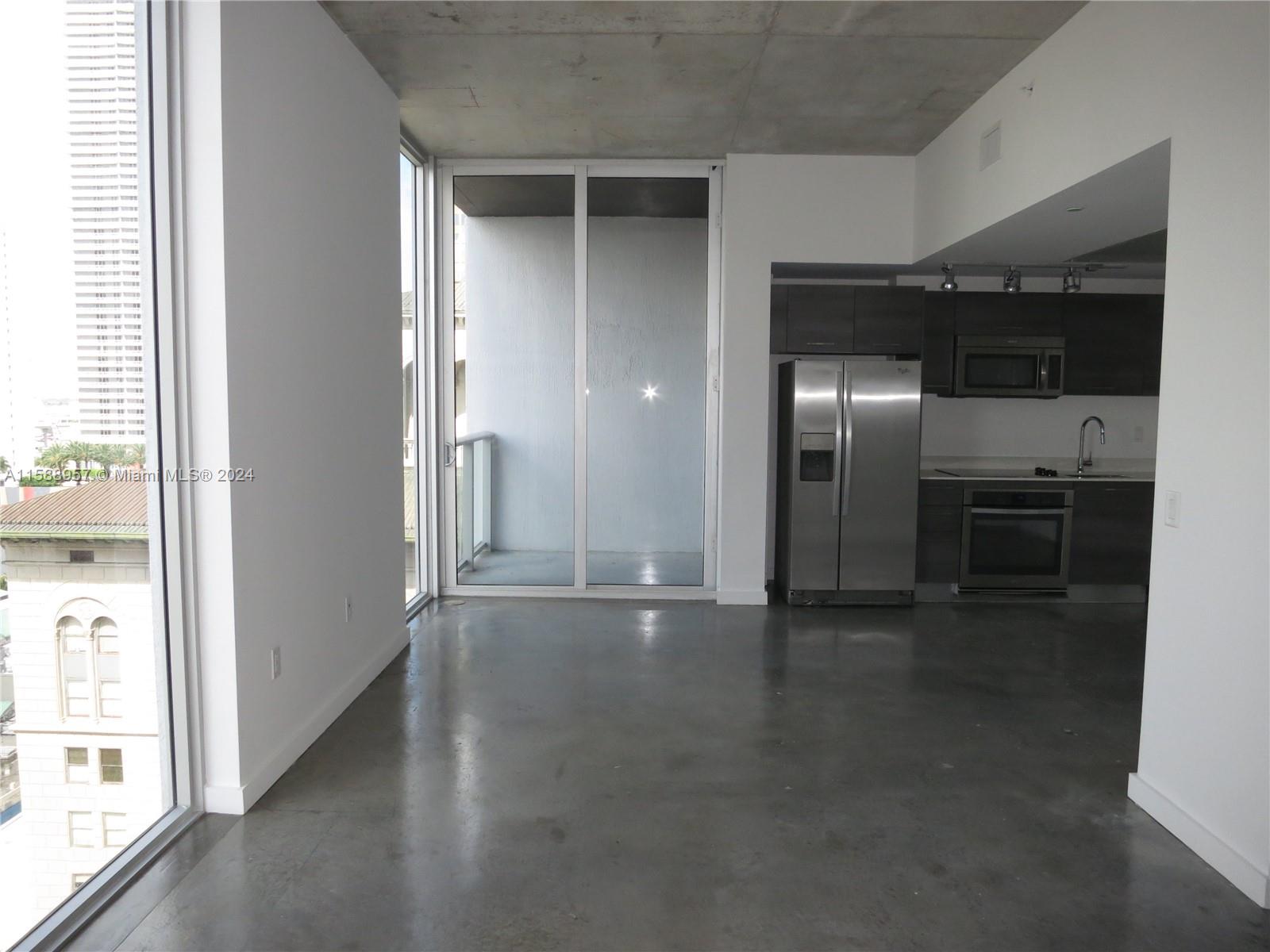 An open-concept apartment features a kitchen with stainless steel appliances and polished concrete floors — 151 SE 1 St # 1704, Miami FL 33131, MIAMI, FL