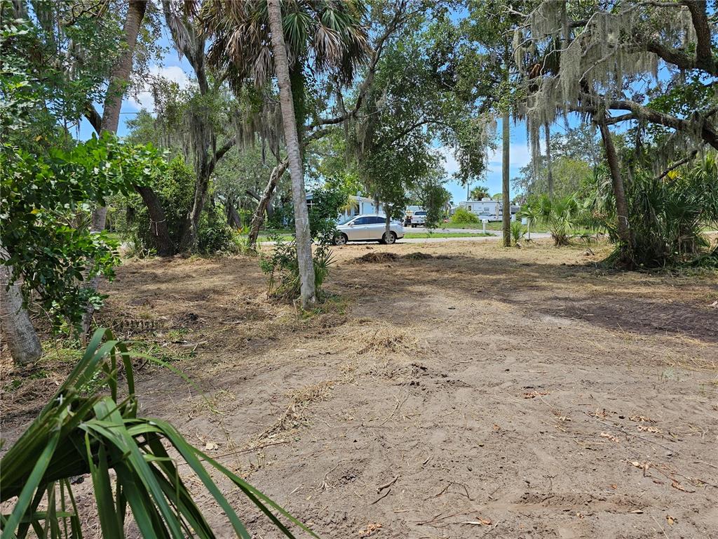 A cleared, sandy residential lot with scattered trees and a car parked in the background — 2504, 2506, and 2508 RIVER BEND DRIVE, RUSKIN, FL
