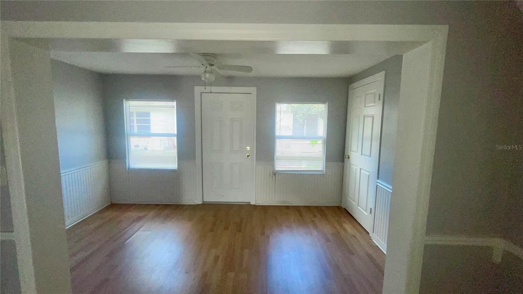 A room with light wood flooring, white wainscoting, two windows, and a white door — 4211 SHELDON PLACE UNIT 4211, NEW PORT RICHEY, FL