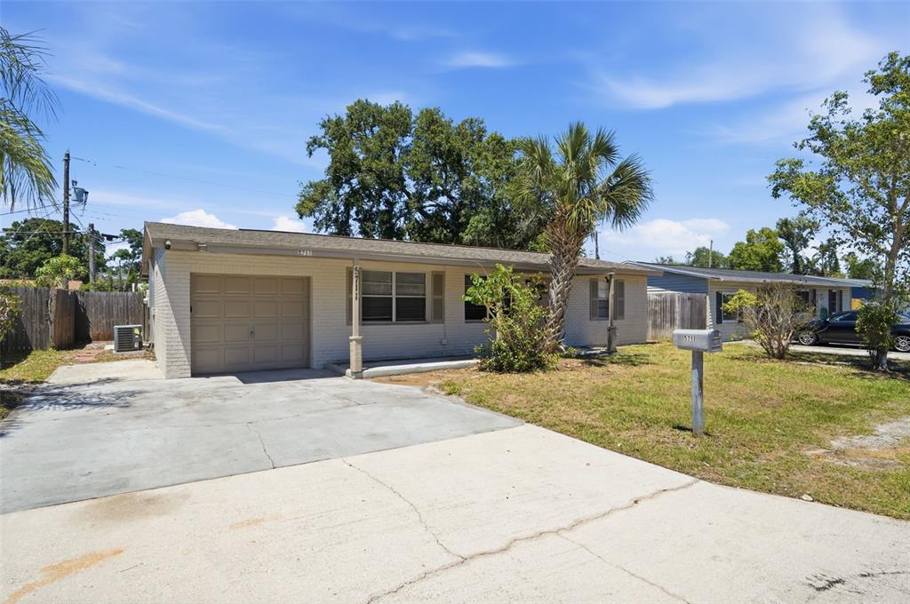 A single-story brick house with a concrete driveway, a garage, and a palm tree — 5711 64TH AVENUE N, PINELLAS PARK, FL