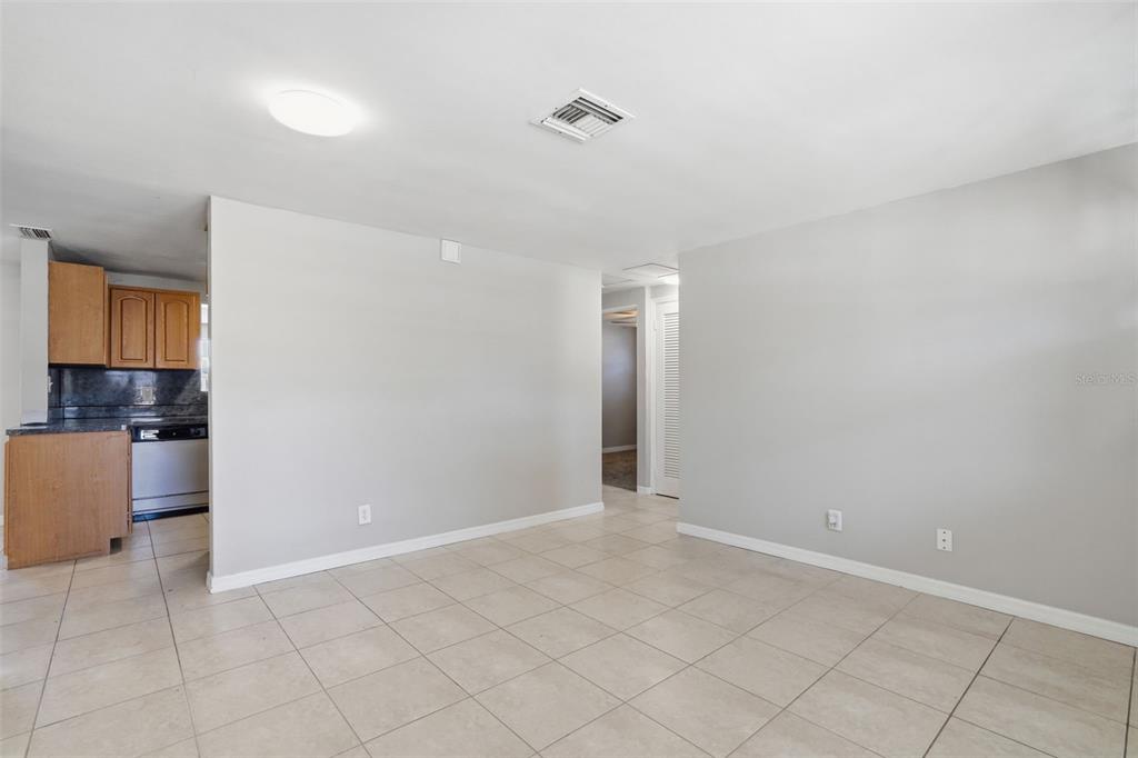 A view of a living area with light tile flooring and an adjacent kitchen — 5711 64TH AVENUE N, PINELLAS PARK, FL
