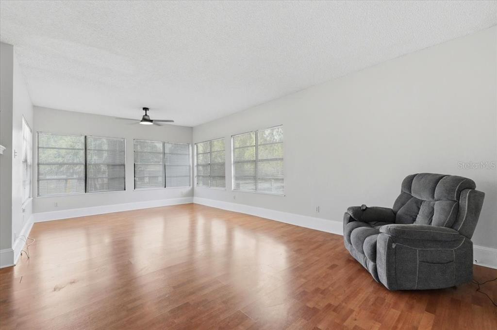 A spacious living room features light gray walls, hardwood floors, and a single gray recliner — 1950 RICHMOND ROAD, LAKELAND, FL