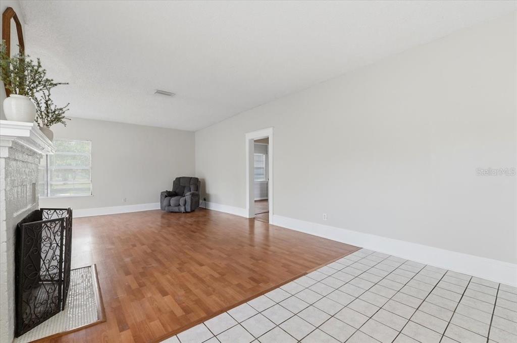 A living room features hardwood floors, a fireplace, and a doorway leading to another room — 1950 RICHMOND ROAD, LAKELAND, FL