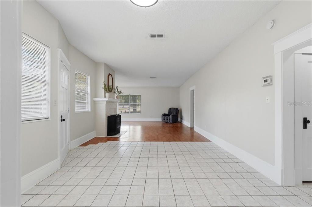 A room with white tiled flooring transitioning to hardwood, a fireplace, and a gray chair — 1950 RICHMOND ROAD, LAKELAND, FL