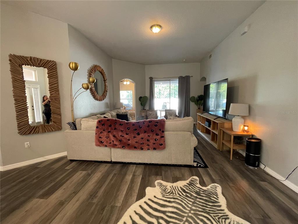A living room features a sectional sofa, a large television, and wood-look flooring — 4314 BIEL COURT, KISSIMMEE, FL