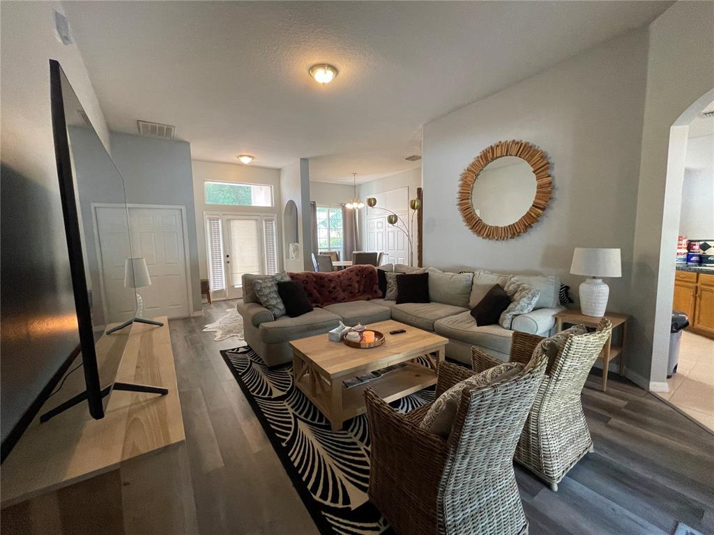 A living room features a sectional sofa, wicker chairs, a coffee table, and a mirror — 4314 BIEL COURT, KISSIMMEE, FL
