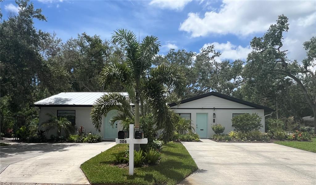 A duplex with two light blue doors, concrete driveways, and a palm tree in the yard — 302 19TH ST. EAST, BRADENTON, FL