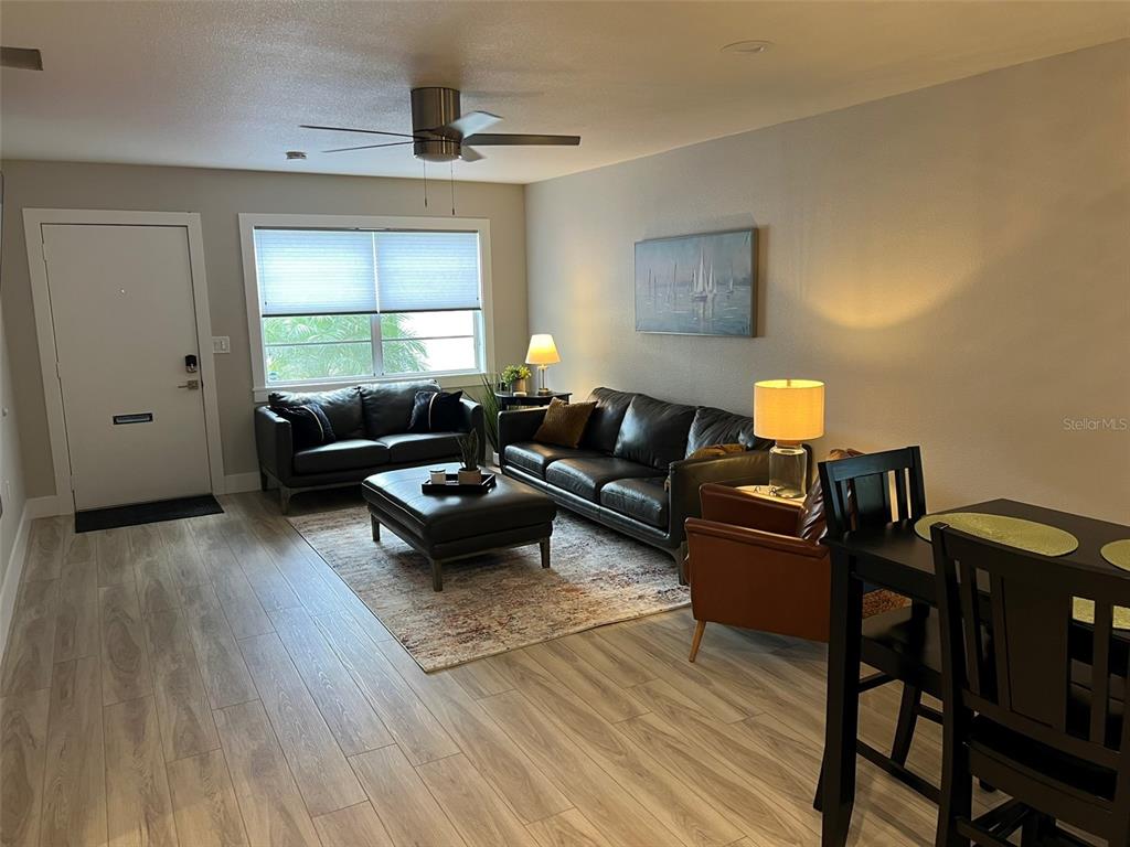 A living room features light wood-look flooring, a leather sofa set, and a dining area — 302 19TH ST. EAST, BRADENTON, FL