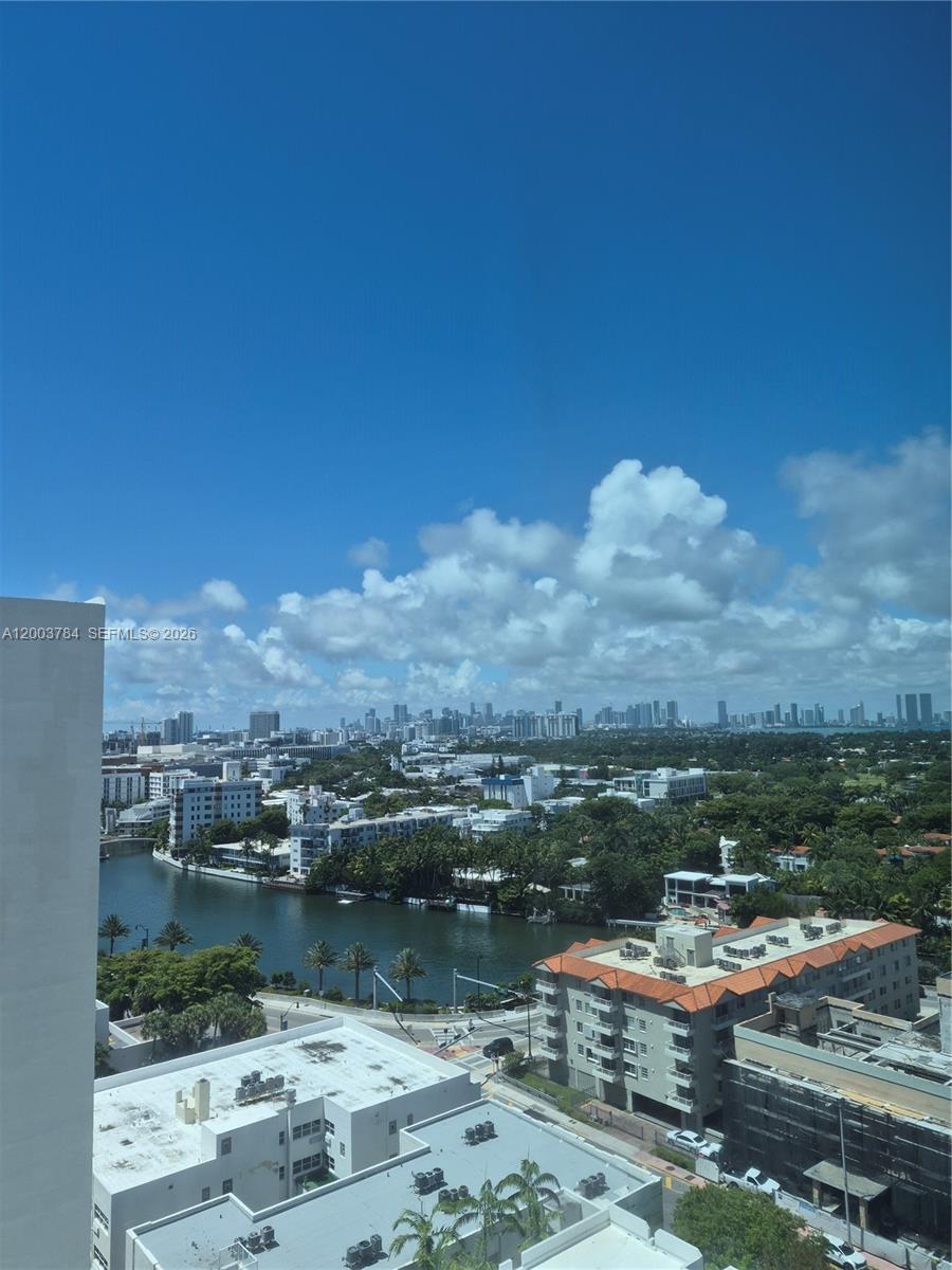 An elevated view shows a waterway, surrounding buildings, and a distant city skyline under blue skies — 2655 Collins Ave # 2406, Miami Beach FL 33140, MIAMI BEACH, FL