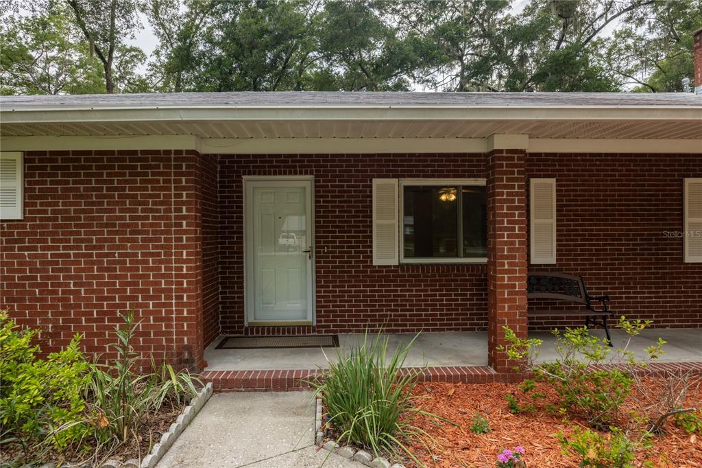 The exterior of a brick house features a covered front porch and a white door — 130 SW 75TH TERRACE, GAINESVILLE, FL