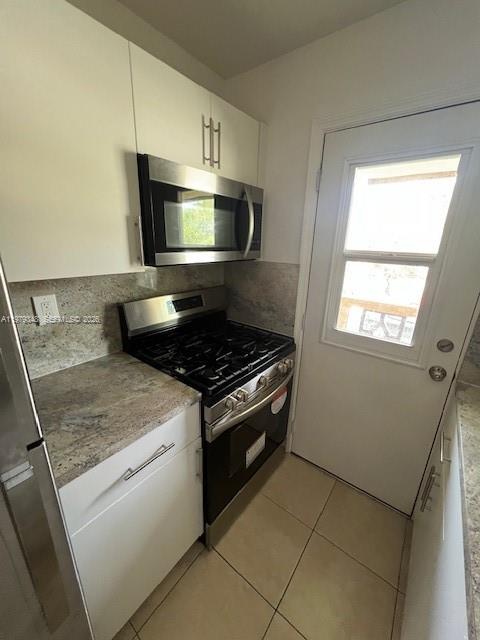 A stainless steel gas range and microwave are installed in a kitchen with granite countertops — 3901 SW 78th Ct # 219, Miami FL 33155, MIAMI, FL