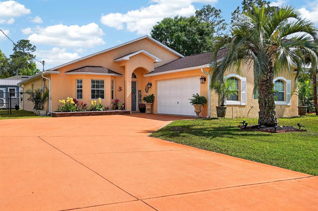 A peach-colored single-story house with a large concrete driveway and a palm tree — 39 WHEELING LANE, PALM COAST, FL