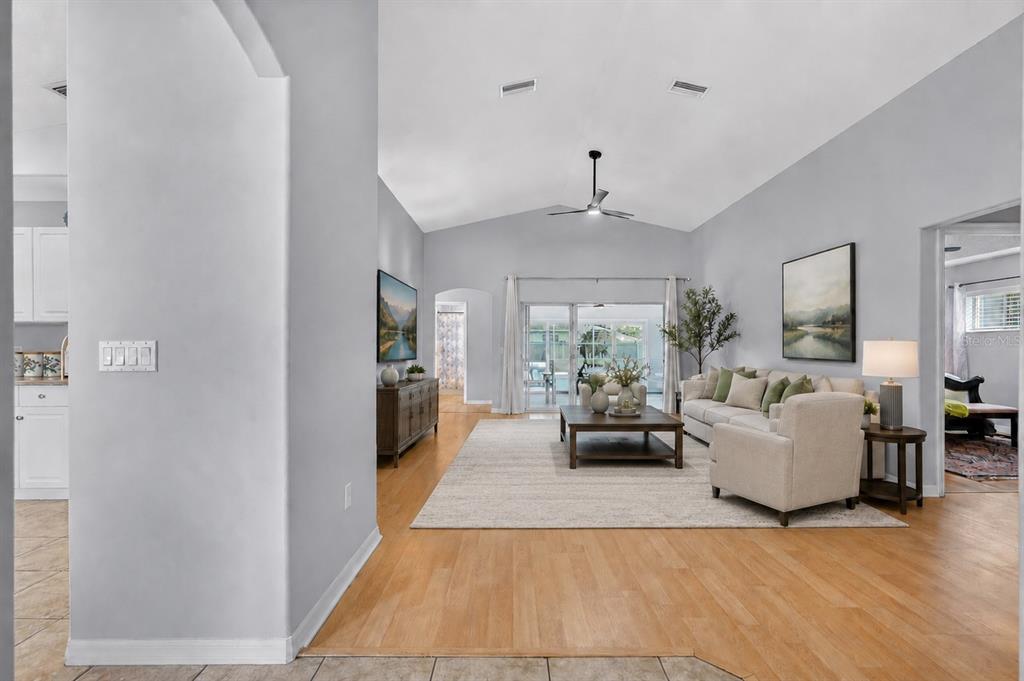 A bright living room features light wood floors, a vaulted ceiling, and sliding glass doors — 39 WHEELING LANE, PALM COAST, FL