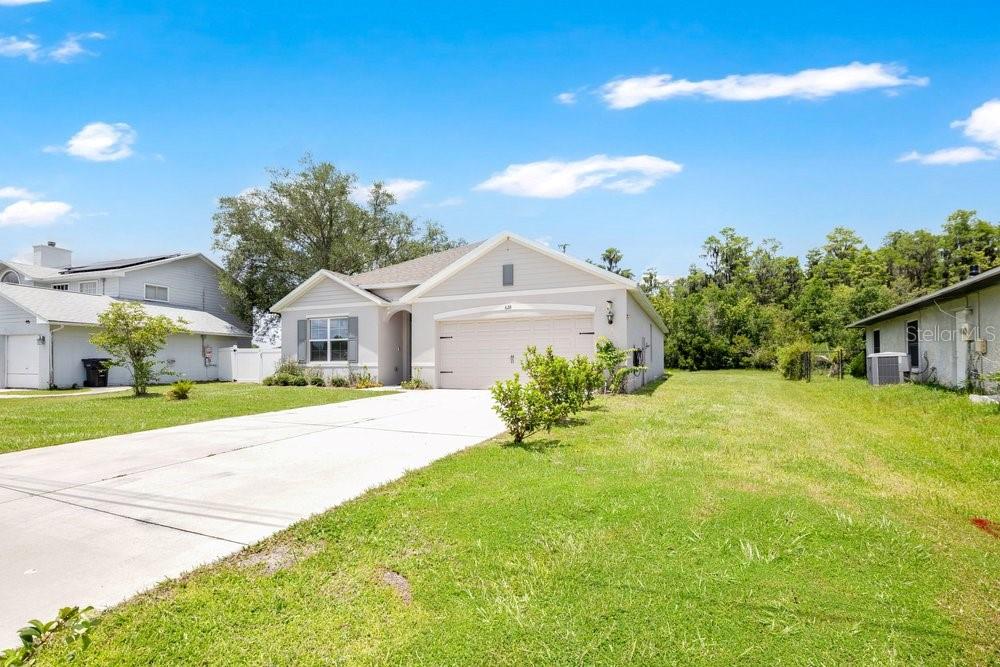 A single-story house with a beige garage and light siding sits on a grassy lot — 628 REINDEER DRIVE, KISSIMMEE, FL