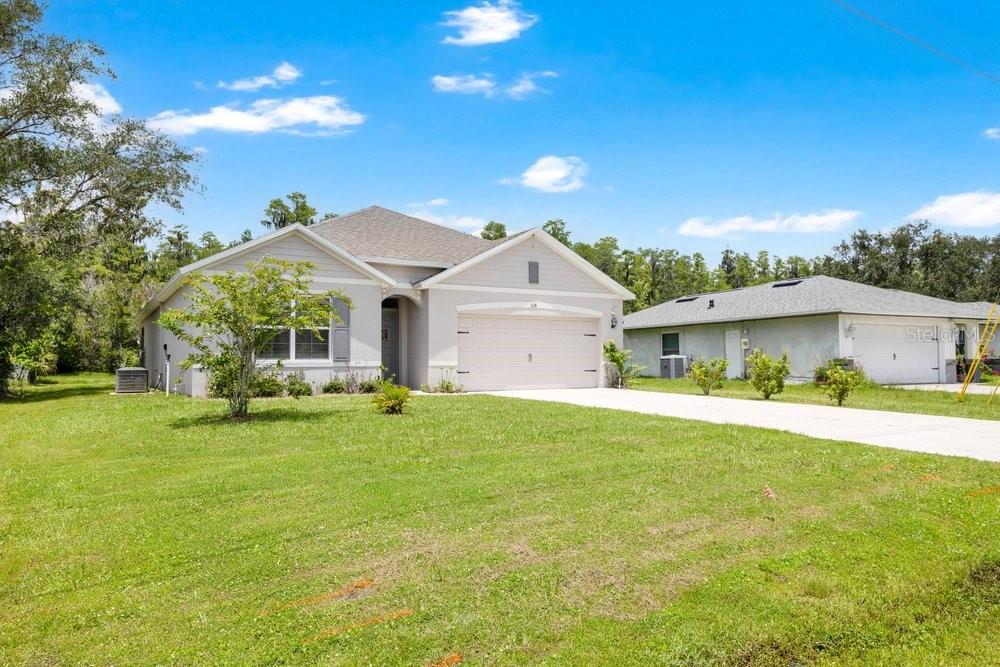 A single-story suburban house with a light-colored exterior, a two-car garage, and a grassy lawn — 628 REINDEER DRIVE, KISSIMMEE, FL