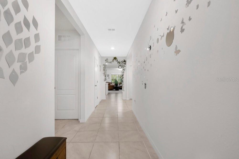 A bright hallway with light tile flooring leads toward an open living area — 628 REINDEER DRIVE, KISSIMMEE, FL